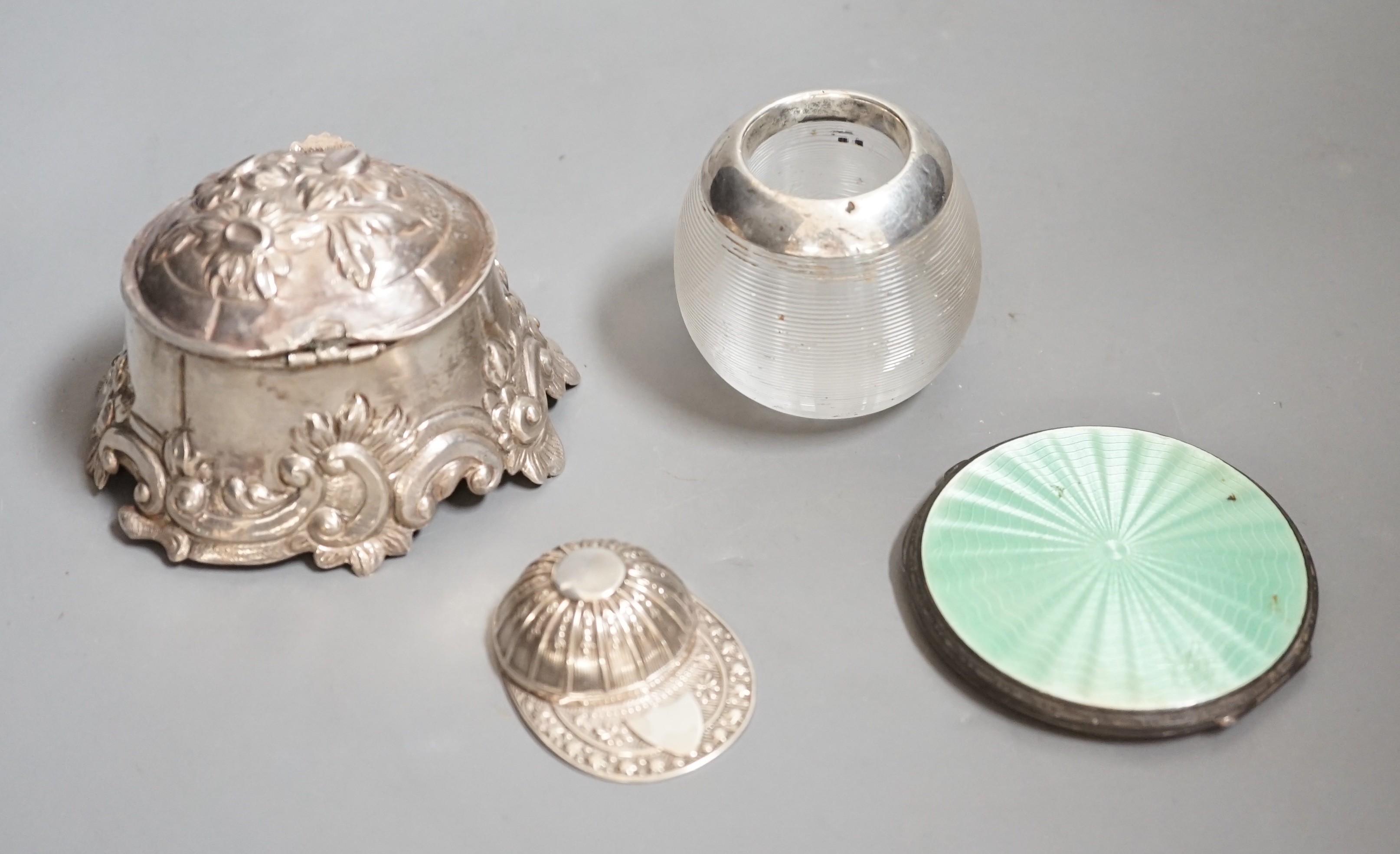 A 19th century continental white metal salt?, with hinged cover, length 93mm, a modern silver jockey cap caddy spoon, a silver and enamel compact and a white metal mounted glass match strike.